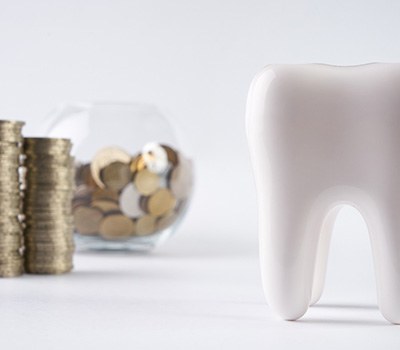 Tooth next to a bowl of coins