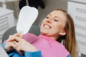 Woman looking at her teeth in dental mirror