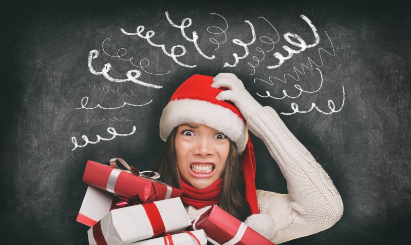 woman stressed wearing Santa hat and holding presents